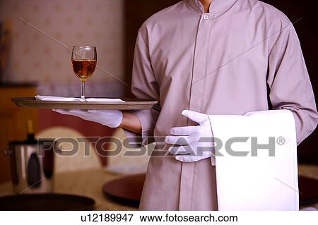 Young waiter holding a tray with a glass of red wine and towel, close-up View Large Photo Image Stock Photo - Young waiter holding a tray with a glass of red wine and towel, close-up. Fotosearch