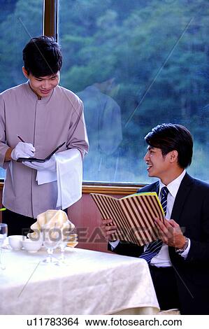Picture - Young waiter serving for the customer and smiling together. Fotosearch