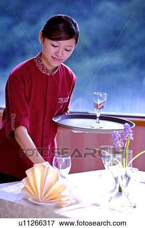 Young waitress holding a tray with wine glass and putting wine glass on the table View Large Photo Image Stock Photo - Young waitress holding a tray with wine glass and putting wine glass on the table. Fotosearch
