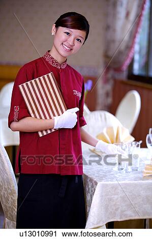 Young waitress holding the menu and smiling at the camera View Large Photo Image Stock Image - Young waitress holding the menu and smiling at the camera. Fotosearch