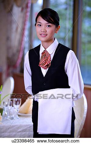 Stock Photography - Young waitress holding the towel and looking at the camera. Fotosearch