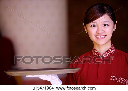 Young waitress holding the tray and smiling at the camera View Large Photo Image Picture - Young waitress holding the tray and smiling at the camera. Fotosearch