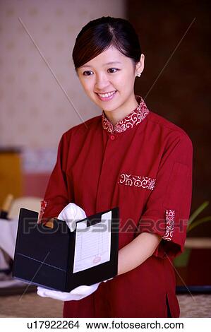Picture - Young waitress showing the bill and smiling. Fotosearch