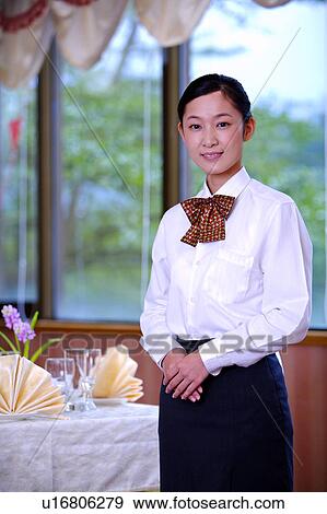 Stock Photo - Young waitress well-dressed with hands folded in front and smiling at the camer. Fotosearch