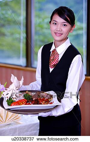 Stock Photo - Young wiatress holding a tray with serving dish and smiling at the camera. Fotosearch