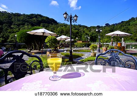 Stock Photograph - A glass of juice on the table in a garden restaurant. Fotosearch
