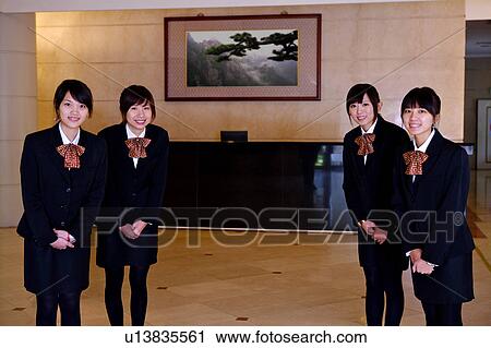 Stock Image - Four young waitresses welcoming guests at the lobby. Fotosearch