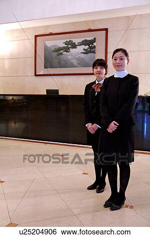 Two young waitress standing with hands folded in front and smiling at the camera View Large Photo Image Stock Photograph - Two young waitress standing with hands folded in front and smiling at the camera. Fotosearch