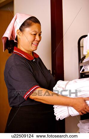 Picture - Waitress holding a stack of folded towel and smiling. Fotosearch