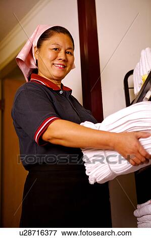Waitress holding a stack of towels and smiling at the camera View Large Photo Image Stock Photo - Waitress holding a stack of towels and smiling at the camera. Fotosearch