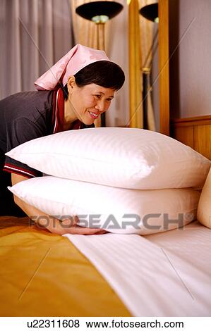 Stock Photo - Waitress holding the pillow and smiling. Fotosearch