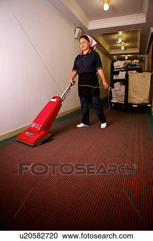 Stock Image - Waitress using cleaning equipment to clean the corridor. Fotosearch