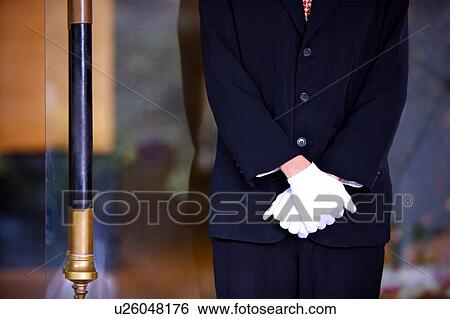 Stock Photograph - Young woman standing with hands folded in front. Fotosearch