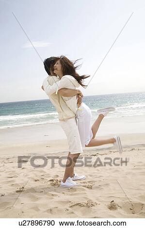 Stock Image - Couple hugging each other on a beach. Fotosearch