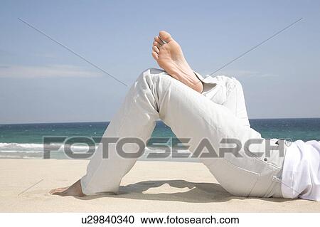 Stock Image - Foot of man lying on a beach. Fotosearch