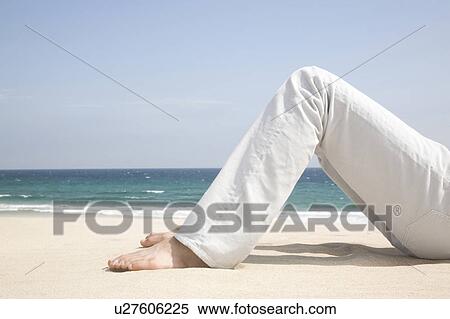 Stock Photography - Foot of man lying on a beach. Fotosearch