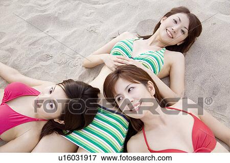 Stock Photo - Japanese weman lying on a beach in swimsuit. Fotosearch