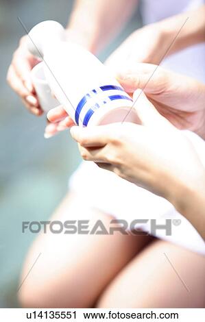 Stock Image - Hand of woman pouring a Japanese sake. Fotosearch