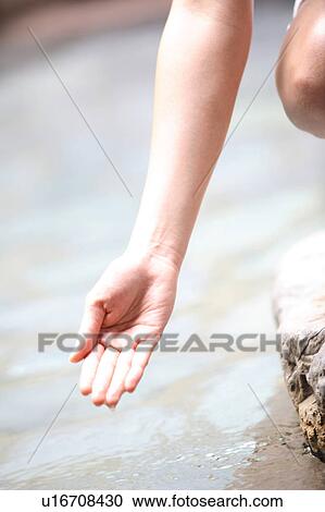 Stock Image - Hand of woman trying to touch a hot water. Fotosearch