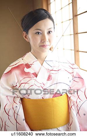 Stock Image - Japanese woman putting on a yukata. Fotosearch