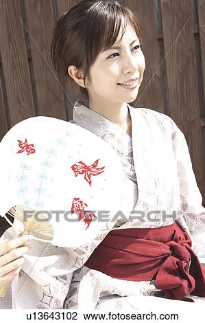 Stock Image - Japanese woman putting on kimono. Fotosearch