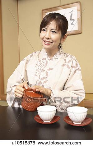 Stock Photo - Japanese woman putting on kimono. Fotosearch