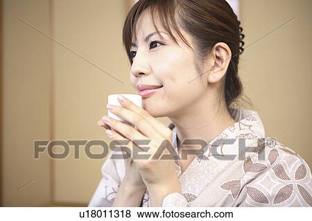 Stock Photo - Japanese woman putting on kimono. Fotosearch