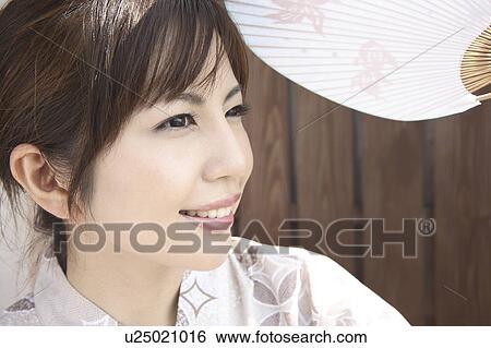 Stock Photograph - Japanese woman putting on kimono. Fotosearch