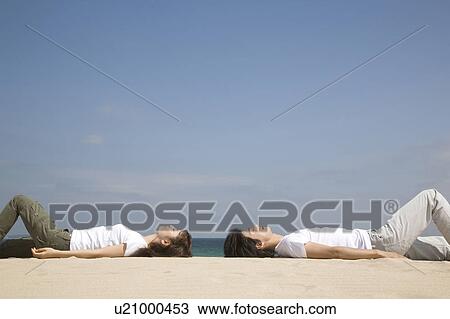 Stock Image - Japanese couple lying on a beach. Fotosearch