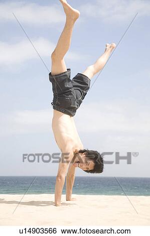 Stock Photograph - Japanese man doing gymnastics on a beach. Fotosearch