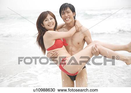 Stock Image - Japanese man lifting up lover. Fotosearch