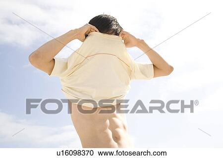 Japanese man taking off a shirt View Large Photo Image Stock Image - Japanese man taking off a shirt. Fotosearch