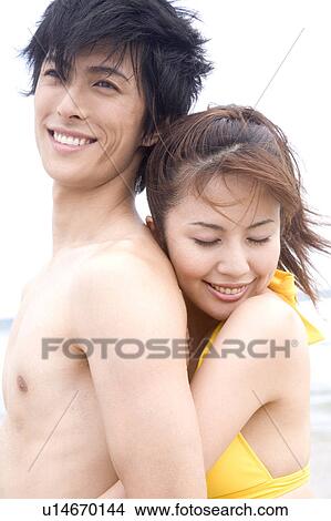 Picture - Japanese woman embraces lover from back. Fotosearch