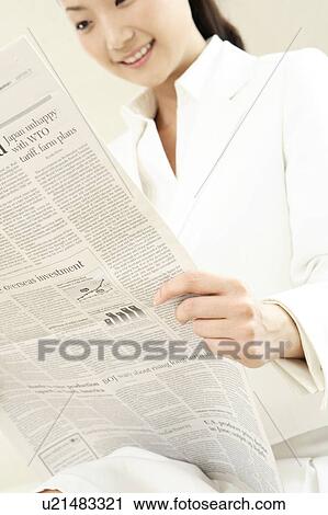 Stock Image - Office lady reading a newspaper. Fotosearch