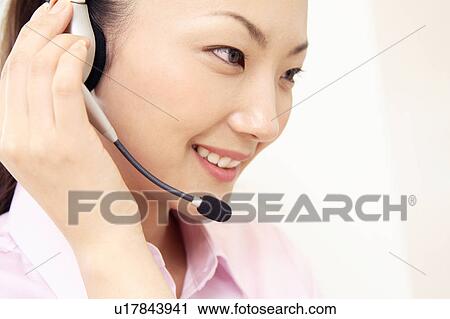 Stock Image - Office lady talking with headset. Fotosearch