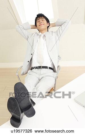 Stock Photograph - Office worker riding his foot on a desk. Fotosearch