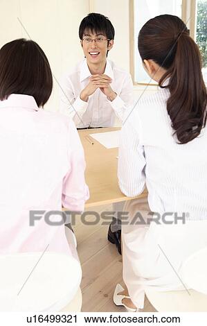 Stock Image - Office workers having a brief meeting. Fotosearch