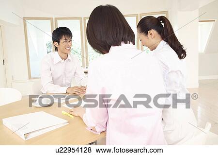 Stock Photo - Office workers having a brief meeting. Fotosearch