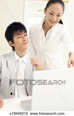 Stock Photography - Office workers looking at PC monitor. Fotosearch
