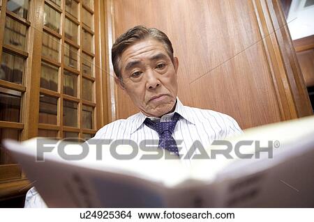 Picture - Japanese executive reading a book. Fotosearch