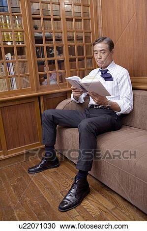 Stock Image - Japanese executive reading a book. Fotosearch
