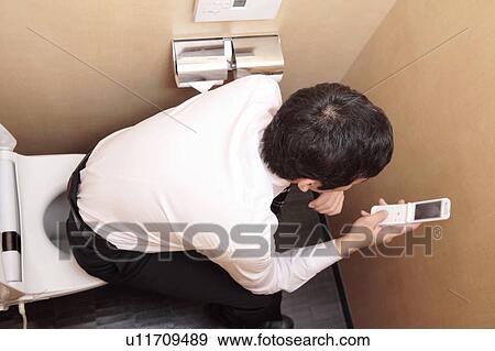 Japanese office worker checking cell phone in a restroom View Large Photo Image Stock Photo - Japanese office worker checking cell phone in a restroom. Fotosearch