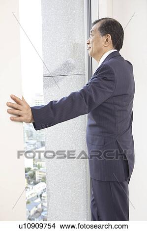 Picture - Chief executive officer looking at outside from room. Fotosearch