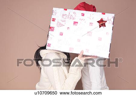 Stock Image - Couple hidden by gift box. Fotosearch