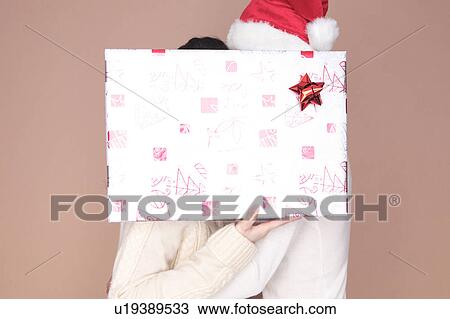 Stock Image - Couple hidden by gift box. Fotosearch