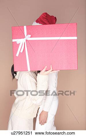 Stock Image - Couple hidden by gift box. Fotosearch