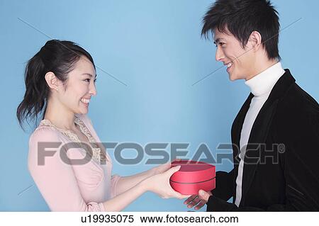 Stock Photography - Woman handing a gift to lover. Fotosearch