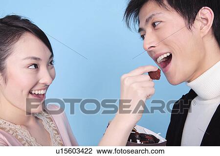 Stock Image - Woman let a man eat chocolate. Fotosearch