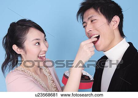 Stock Image - Woman let a man eat chocolate. Fotosearch