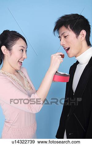 Stock Photo - Woman let a man eat chocolate. Fotosearch